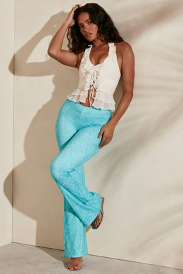 Flare trousers in teal print with ivory ruffle crop top.